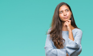 Woman making a questioning gesture on light teal background