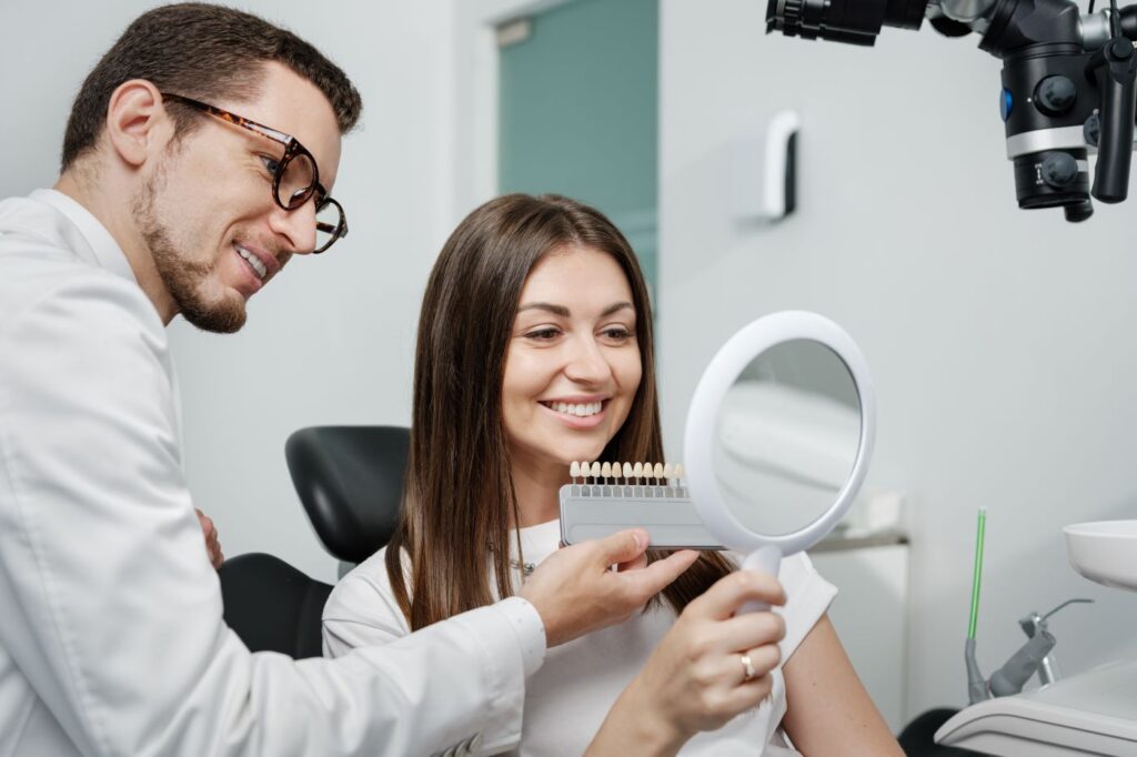 A woman looking at a tooth shade selector at the dentist's office.